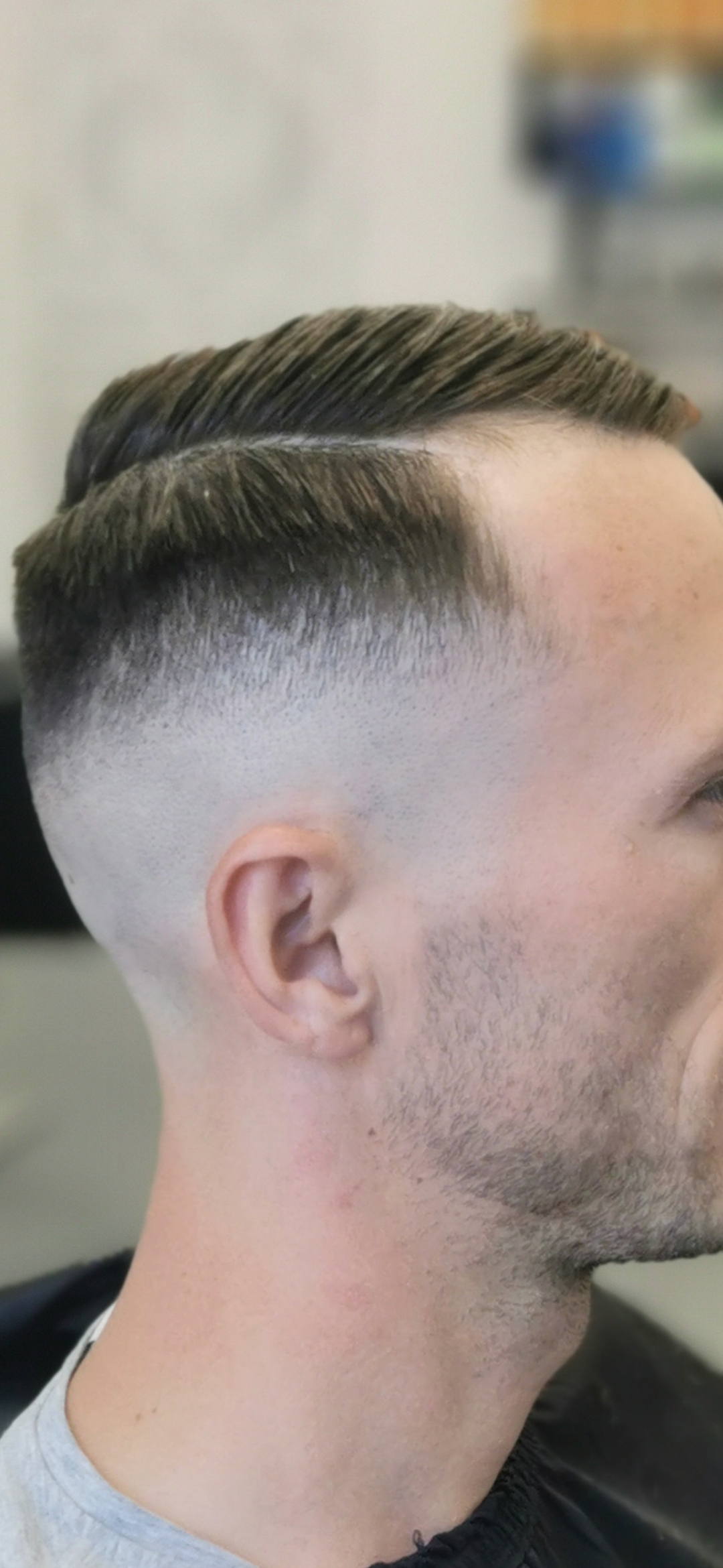 Strakke skin fade met scheiding, van opzij
